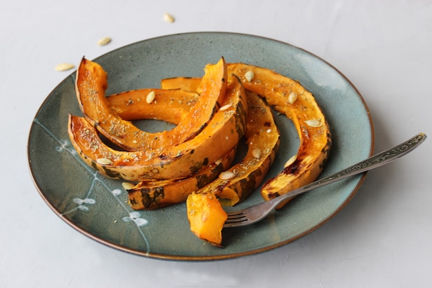 Rodajas de calabaza al horno, espolvoreadas con hierbas secas, rociadas con aceite de oliva.