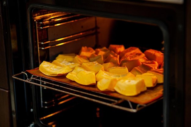 Rodajas de calabaza horneadas en una bandeja para hornear en el horno. Comida casera, comida vegana, comida sana, verduras de naranja en una bandeja para hornear y servilleta, verduras rústicas al horno, arte pop, postre durante una dieta