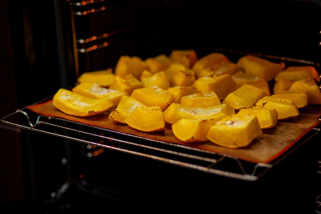 Rodajas de calabaza horneadas en una bandeja para hornear en el horno. Comida casera, comida vegana, comida sana, verduras de naranja en una bandeja para hornear y servilleta, verduras rústicas al horno, arte pop, postre durante una dieta