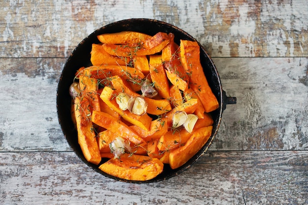 Rodajas de calabaza con tomillo y ajo en una sartén.