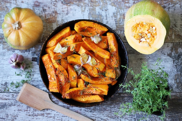 Rodajas de calabaza con tomillo y ajo en una sartén.