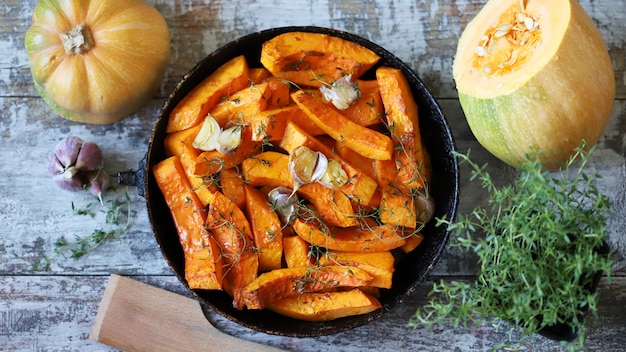 Rodajas de calabaza con tomillo y ajo en una sartén.