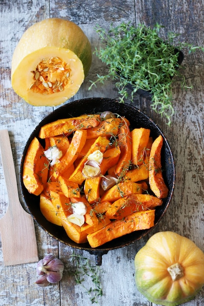 Rodajas de calabaza con tomillo y ajo en una sartén.