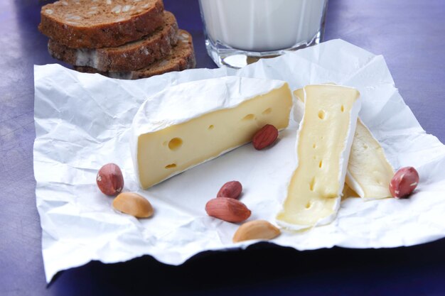 Rodajas de camembert con nueces y frutas sobre papel pergamino sobre un fondo azul Un gran producto para un desayuno Primer plano