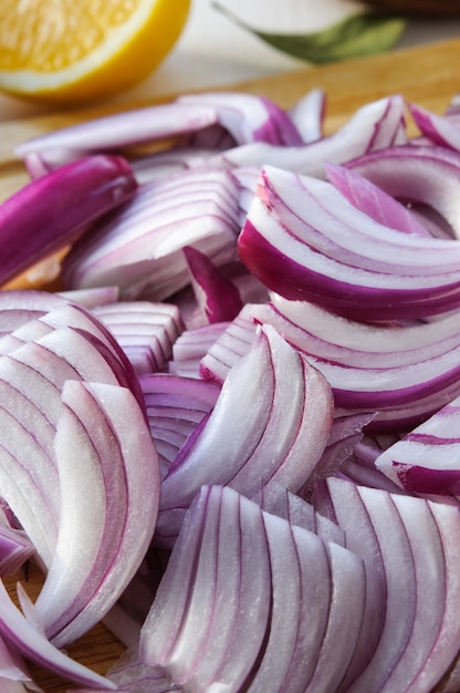 Rodajas de cebolla morada picadas en tabla de madera y limón en