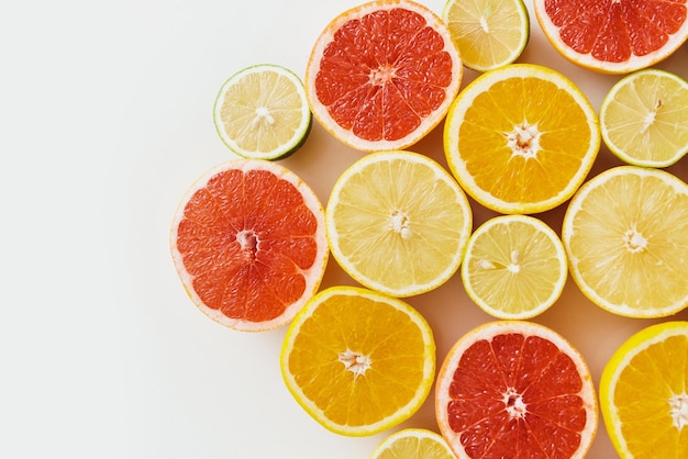 Rodajas de cítricos como pomelo, naranja, limón y lima sobre fondo blanco.