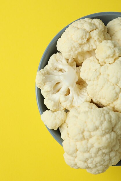 Rodajas de coliflor jugosa fresca en un tazón sobre fondo amarillo