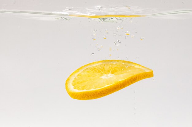 Foto rodajas de fruta naranja cayendo al agua