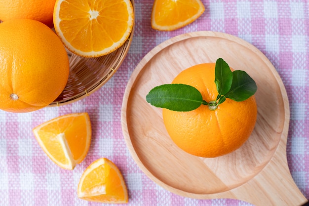 Rodajas de fruta naranja sobre fondo de textura de mantel rosa