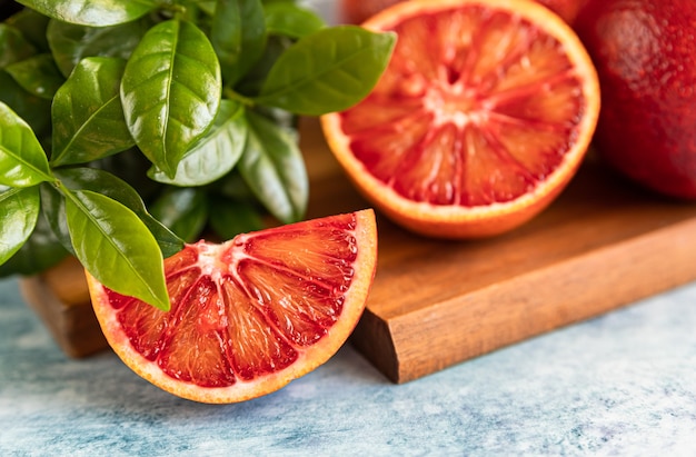 Foto rodajas y jugosas naranjas sanguinas sicilianas maduras enteras con fondo de hormigón azul menta cerrar