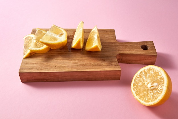 Rodajas de limón amarillo fresco orgánico sobre una tabla para cortar madera