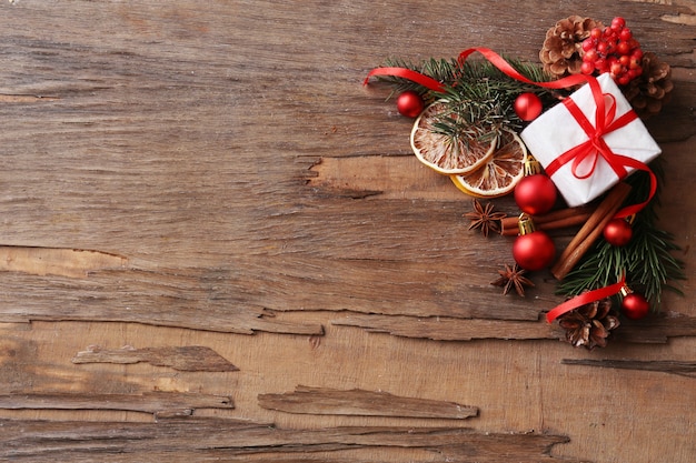 Rodajas de limón seco con caja actual, adornos y ramita de árbol de Navidad sobre fondo de madera rústica