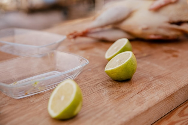 Rodajas de limones y pollo crudo yacen sobre una mesa de madera