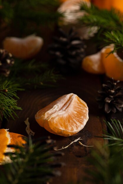 Rodajas de mandarina se encuentran sobre una mesa de madera rodeada de ramitas de abeto verde