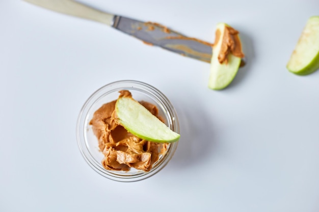 Rodajas de manzana verde con mantequilla de maní sobre fondo blanco bocadillo saludable