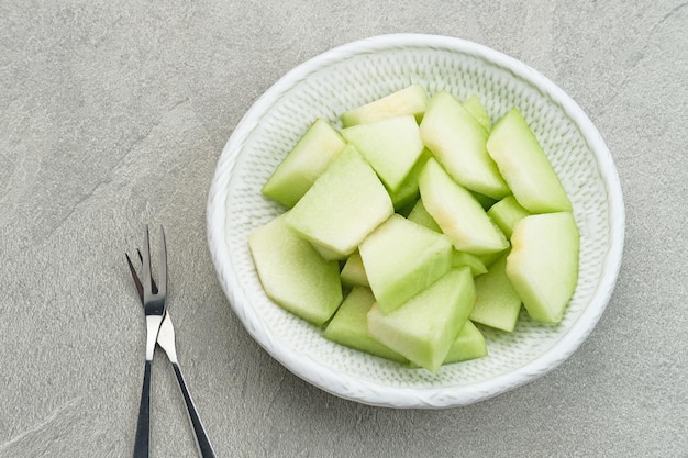 Rodajas de melón cantalupo servido en un plato pequeño sobre fondo gris Foco seleccionado