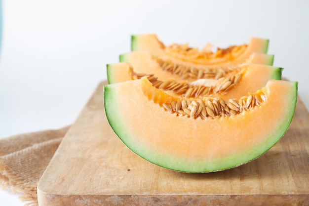 Foto rodajas de melones japoneses en tabla de cortar de madera sobre fondo blanco