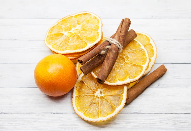 Rodajas de naranja con canela y mandarina sobre fondo de madera, vista superior