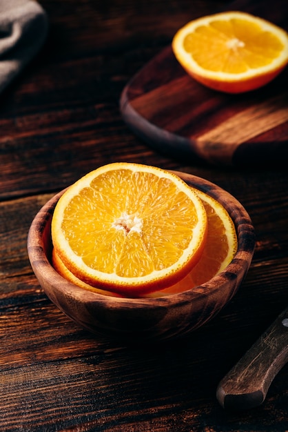 Rodajas de naranja en un cuenco de madera en ambiente rústico