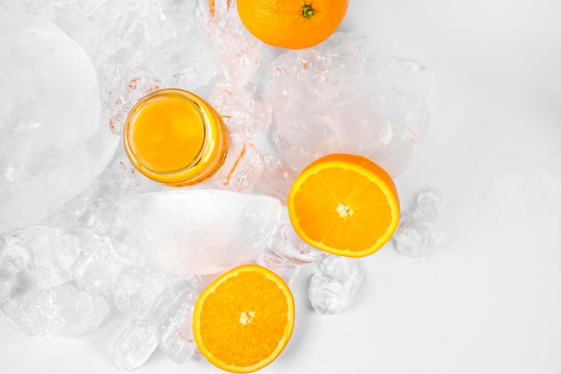 Rodajas de naranja y jugo de naranja sobre hielo sobre fondo blanco.