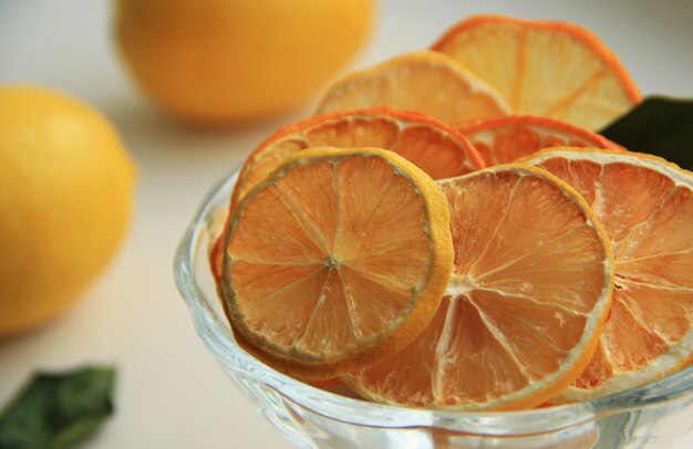 rodajas de naranja y limón secas en un recipiente con limón fresco