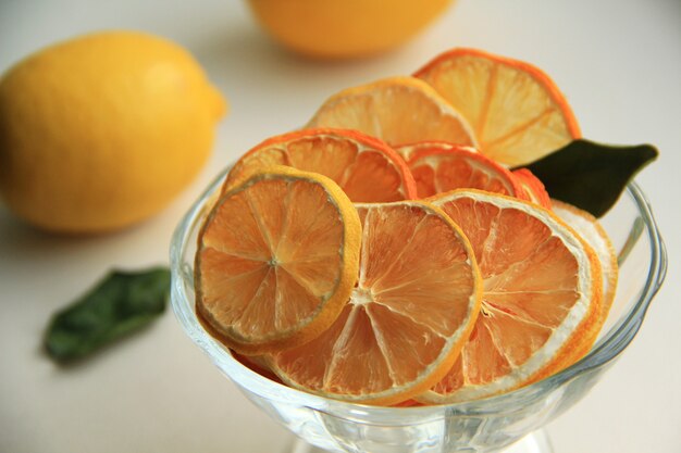 rodajas de naranja y limón secas en un recipiente con limón fresco