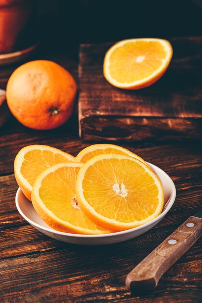 Rodajas de naranja en un plato blanco en un entorno rústico