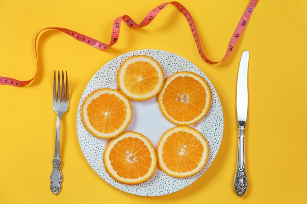 Rodajas de naranja en un plato y un cuchillo con un tenedor. Concepto de dieta