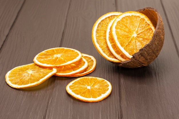 Rodajas de naranja seca esparcidas sobre la mesa Chips de naranja en una cáscara de coco