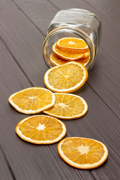 Rodajas de naranja secas se esparcen de un frasco de vidrio sobre la mesa