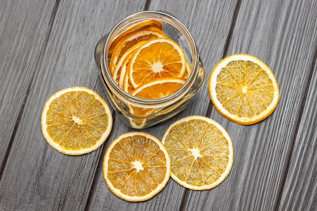 Rodajas de naranja secas sobre la mesa y en un frasco de vidrio