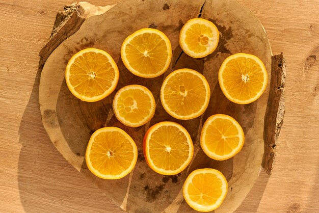 Rodajas de naranjas orgánicas frescas sobre una mesa de cocina de madera.