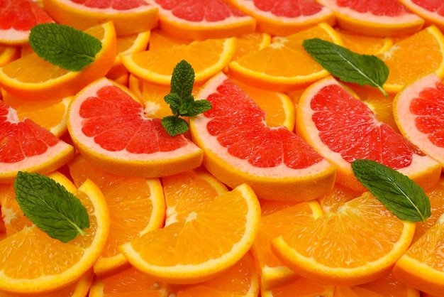 Foto rodajas de naranjas y pomelos y menta como fondo