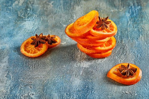 Rodajas de naranjas secas o mandarinas con anís y canela, en una pared azul. Vegetarianismo y alimentación saludable