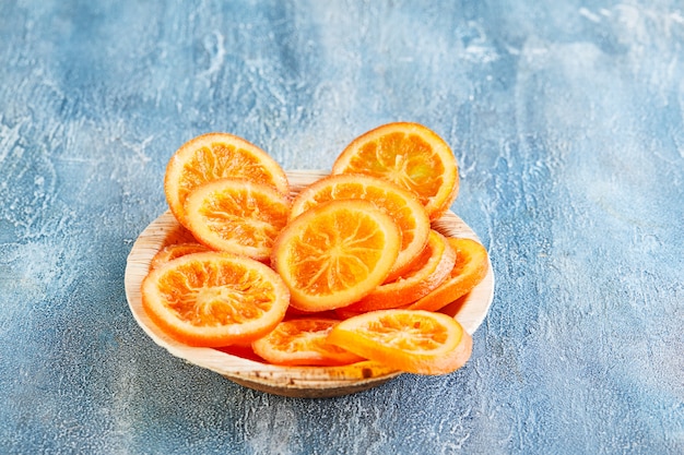Foto rodajas de naranjas secas o mandarinas en un plato de madera. vegetarianismo y alimentación saludable.
