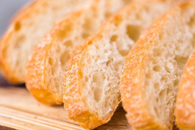 Rodajas de pan ciabatta recién horneado sobre una mesa gris.