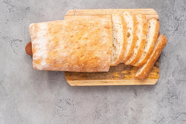 Rodajas de pan ciabatta recién horneado sobre una mesa gris.