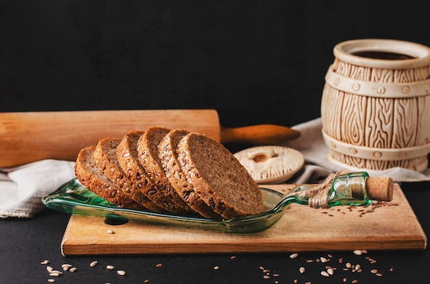 Rodajas de pan integral de centeno con semillas de girasol, lino o lino y sésamo en un plato hecho de botella