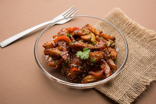 Rodajas de papa y chile con miel, popular receta de entrada de la India y China, adornada con sésamo y cebolla. enfoque selectivo