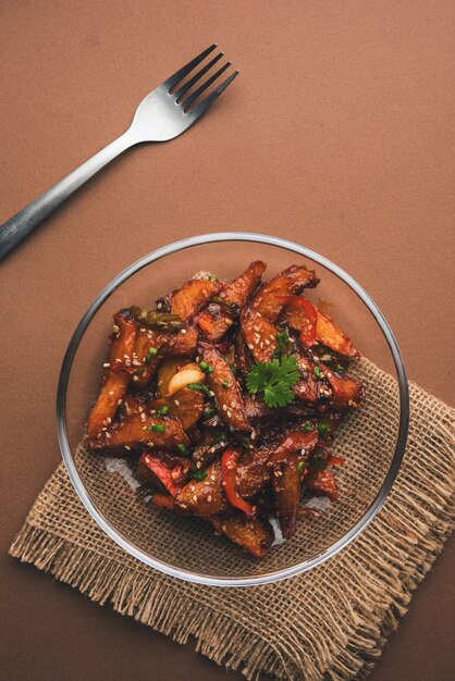 Rodajas de papa y chile con miel, popular receta de entrada de la India y China, adornada con sésamo y cebolla. enfoque selectivo