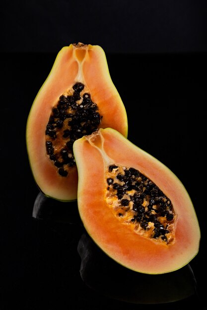 Rodajas de papaya sobre superficie negra brillante