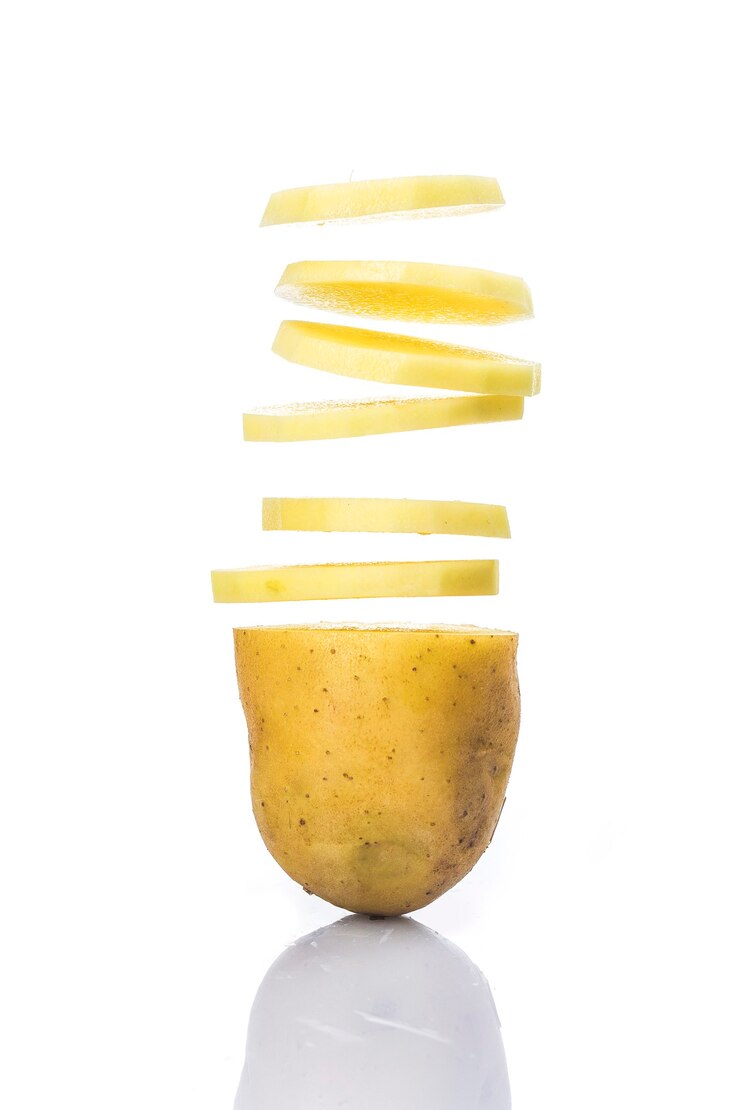 Rodajas de patata convirtiéndose en chips aislado sobre fondo blanco.