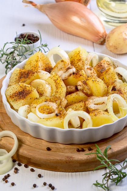 Rodajas de patatas crudas y cebollas con especias