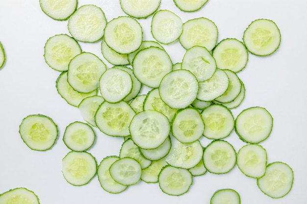 Rodajas de pepino fresco sobre un fondo blanco.