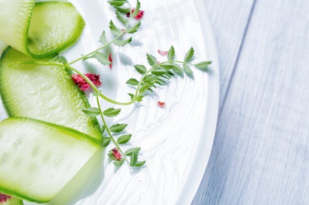 Rodajas de pepino en plato blanco con hojas en plato blanco