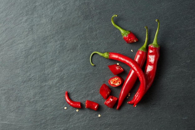 Rodajas de pimiento rojo chileno y semillas sobre una superficie de piedra negra