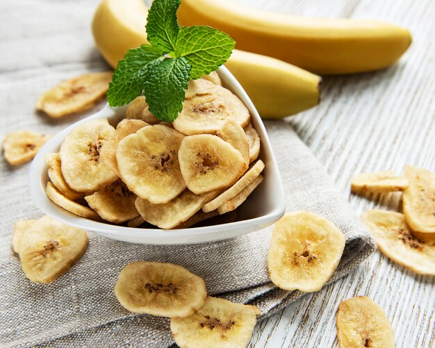 Rodajas de plátano confitado secas o chips sobre un fondo de madera blanca