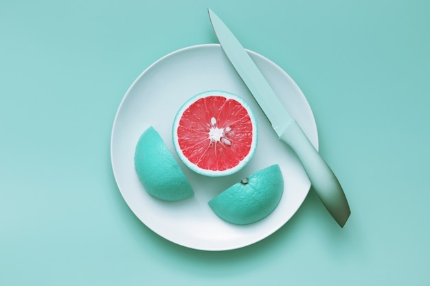 Rodajas de pomelo azul creativas cortadas en plato con cuchillo