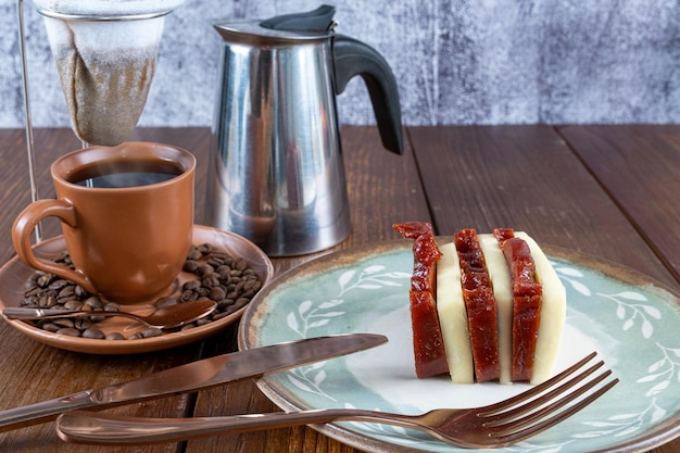 Rodajas de queso dulce y requesón de guayaba junto a una taza de cubiertos, frijoles y una vista lateral del filtro de café de tela