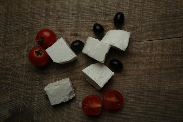 rodajas de queso feta aceitunas negras y tomates cherry sobre un fondo de madera